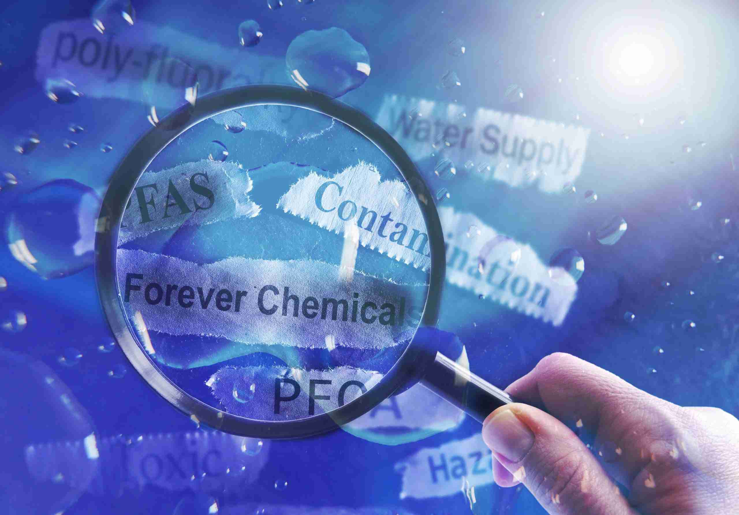 A magnifying glass held over strips of paper representing PFAS in drinking water.